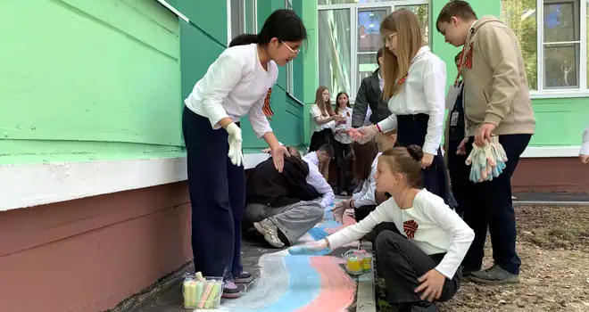 Победная весна: дзержинские ребята нарисовали ленту в цветах Российского триколора во дворе своей школы